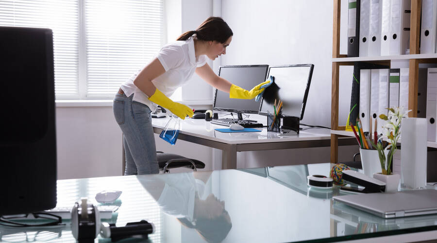Woman Cleaning Computer In Office